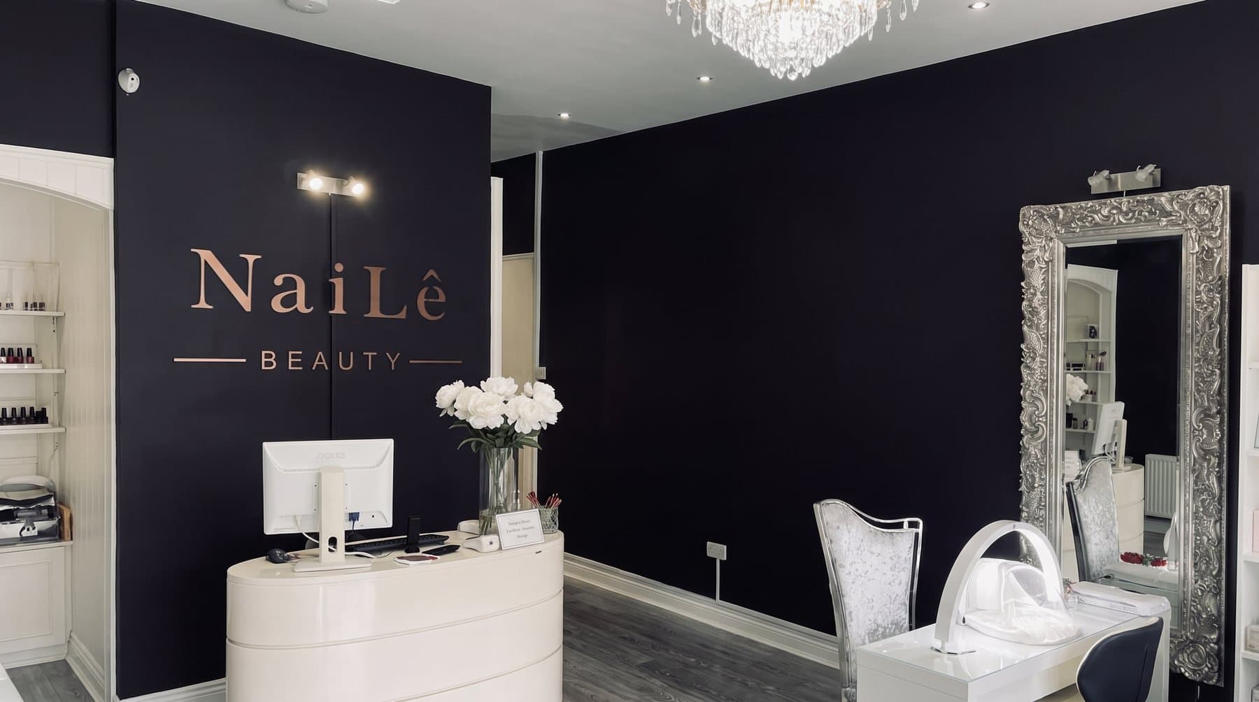 The reception desk with white peonies under the NaiLê Beauty sign