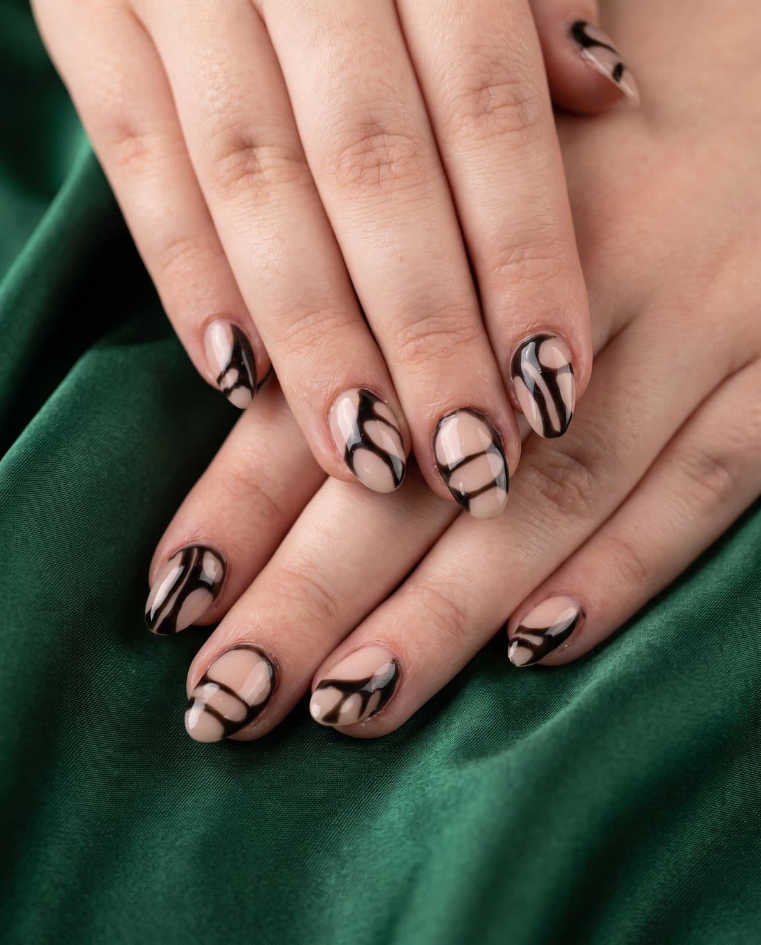 Nude nails with glossy black abstract swirls